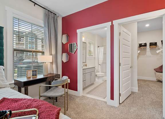 A bedroom with a red accent wall and a white door leading to a bathroom.at 198 Milltown Apartments, Burlington, NC  