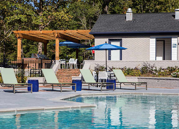 a swimming pool with chairs and umbrellas next to a house at Inverness Cliffs, Alabama