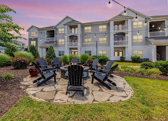 A large building with a patio and chairs around a fire pit. at Concord Ridge Apartments, Concord, NC