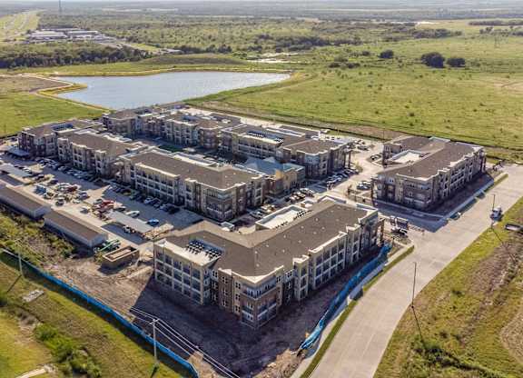 an aerial view of a group of buildings and a lake at Magnolia Grove Apartments, Terrell, 75160