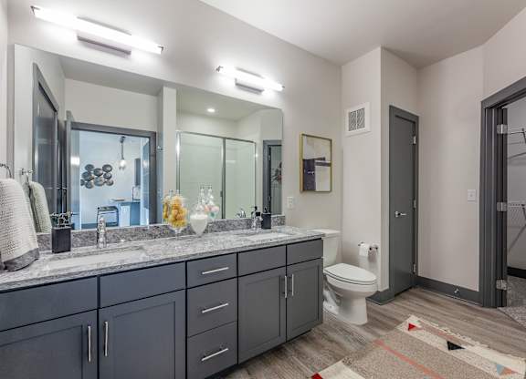 A bathroom with a toilet, sink, and mirror. at Magnolia Grove Apartments, Terrell, 75160