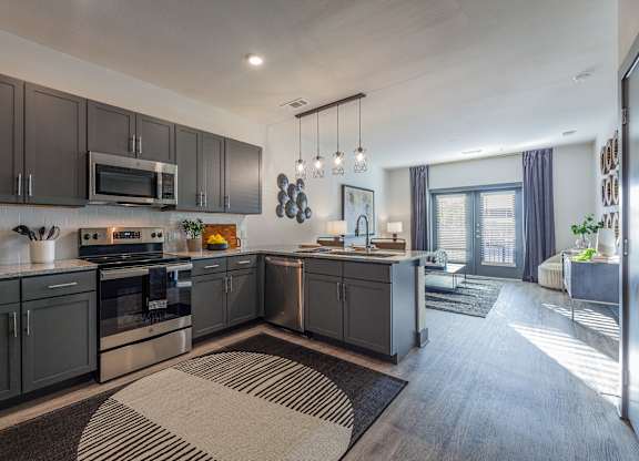 A modern kitchen with dark grey cabinets and a large island. at Magnolia Grove Apartments, Terrell, 75160