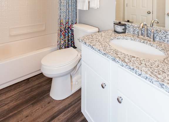 A white bathroom with a toilet, sink, and shower. at WildForest Apartments, Birmingham, 35209