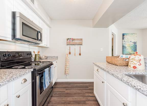 A kitchen with a black stove top oven and white cabinets. at WildForest Apartments, Birmingham, AL