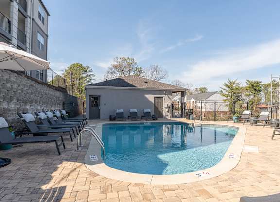 a swimming pool with lounge chairs and a building in the background at WildForest Apartments, Birmingham, AL