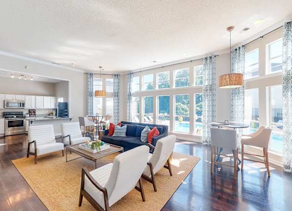 a living room with a couch and chairs and a kitchen with a large window at WildForest Apartments, Alabama, 35209