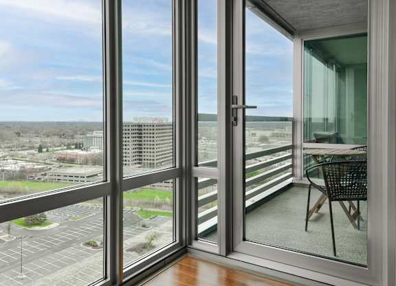 a living room with glass doors and a balcony overlooking a city at Optima Old Orchard Woods, Skokie, IL