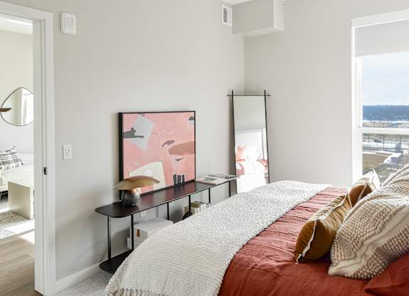 a bedroom with a bed and a desk with a mirror at The Hallon Apartments, Minnesota, 55343