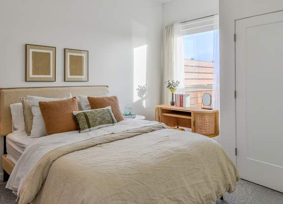 A bedroom with a large bed and two framed pictures on the wall.