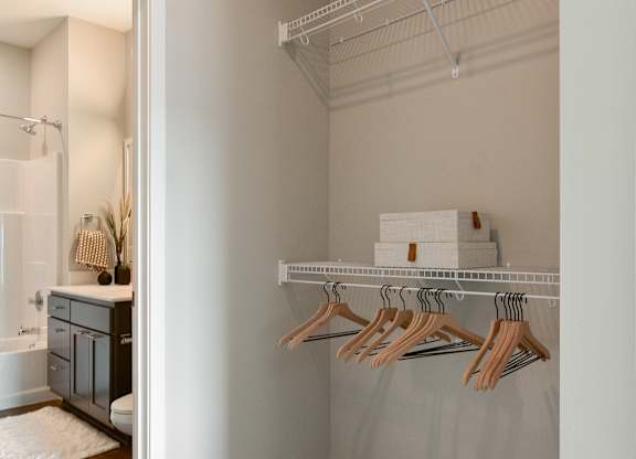 a bathroom with a closet and a rack with wooden hangers at The Hallon Apartments, Minnesota