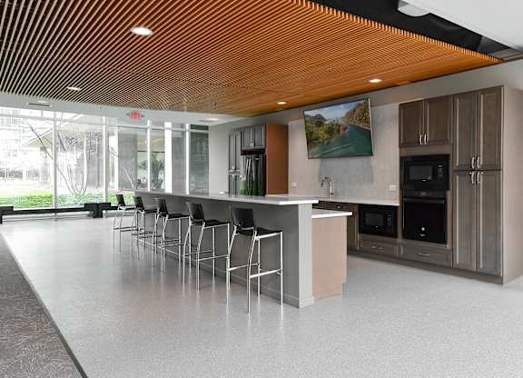 a large kitchen with a bar and stools and a large window at Optima Old Orchard Woods, Skokie, Illinois