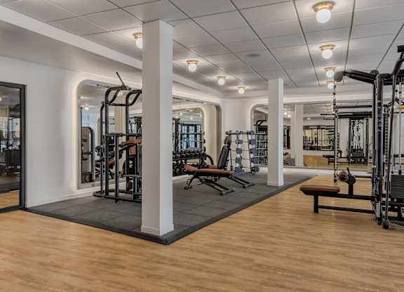 A gym with a variety of equipment including treadmills, weights, and benches.