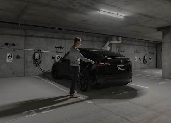 A man is charging an electric car in a parking garage.