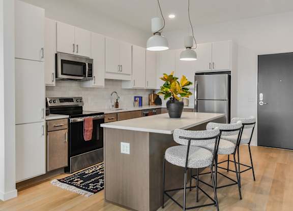 A kitchen with a white counter top and grey chairs.