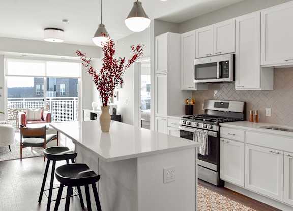 a kitchen with a large white island with three stools at The Hallon Apartments, Minnesota