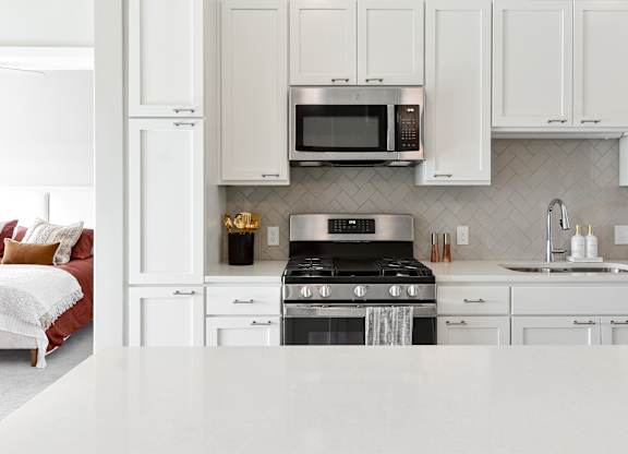 a kitchen with white cabinets and a stove and microwave at The Hallon Apartments, Hopkins