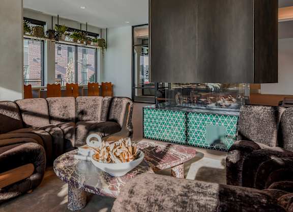 A bowl of chips sits on a coffee table in a room with brown velvet chairs.