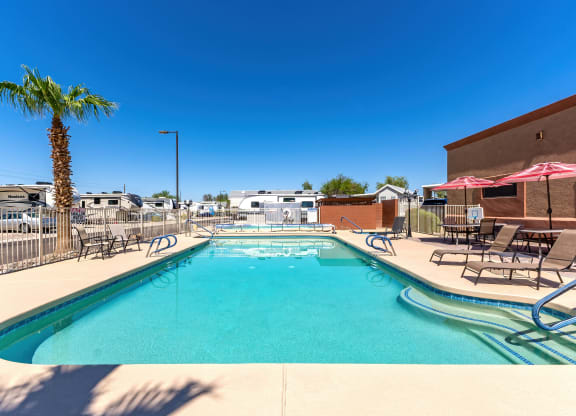 our resort style swimming pool is next to a building and palm tree