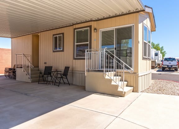 the front of a house with stairs and a patio with chairs
