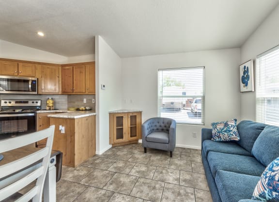 a living room and kitchen with a blue couch and a chair