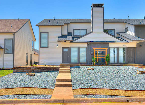 A modern house with a grey exterior and a stone patio in front.