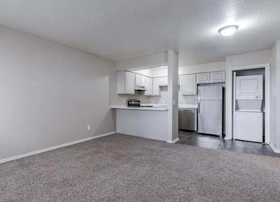 A kitchen area with white appliances and a grey carpet.