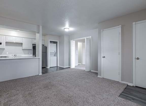 A spacious, empty room with white walls and carpeted floor.