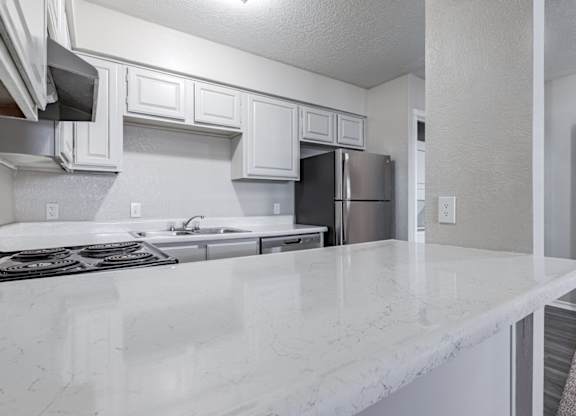 A kitchen with white marble countertops and stainless steel appliances.