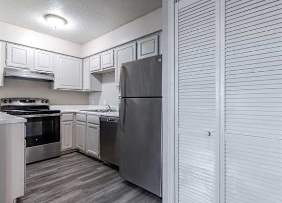 A kitchen with a stove, sink, and refrigerator.