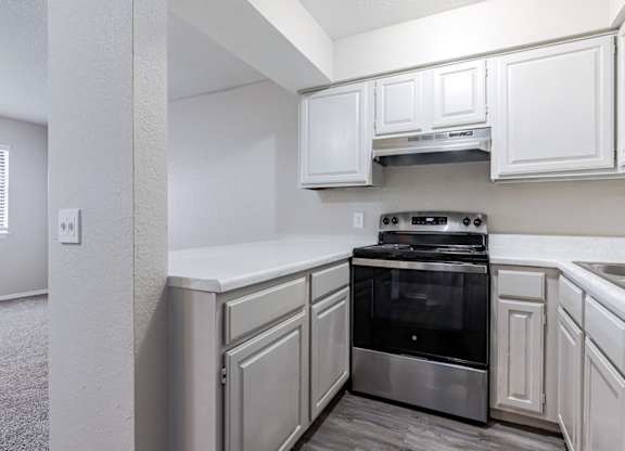 A kitchen with white cabinets and a stainless steel oven.