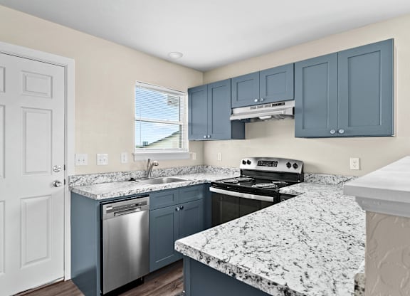 A kitchen with a granite countertop and blue cabinets.