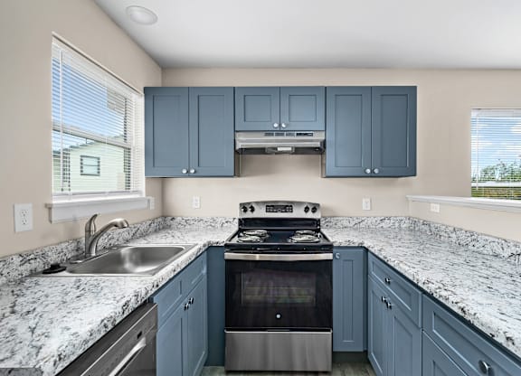 A kitchen with blue cabinets and granite countertops.