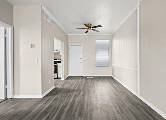 A room with a ceiling fan and wooden flooring.
