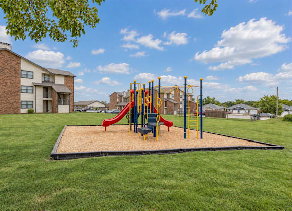 A playground with a red slide and yellow and blue poles.