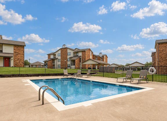 A swimming pool in a residential area with houses in the background.