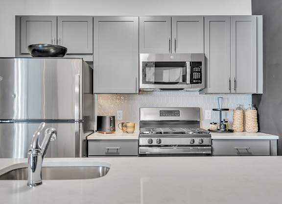 A modern kitchen with a stainless steel refrigerator, microwave, oven, and sink.