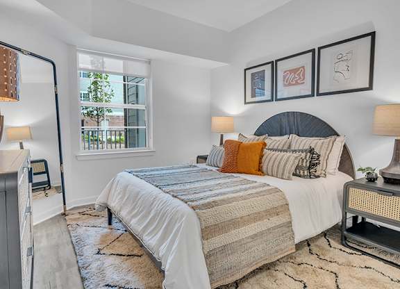 A bedroom with a large bed and a window overlooking a tree.