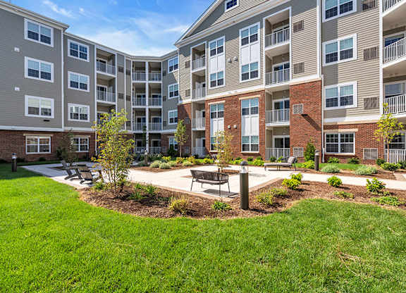 Apartment complex with a green lawn and trees in front.