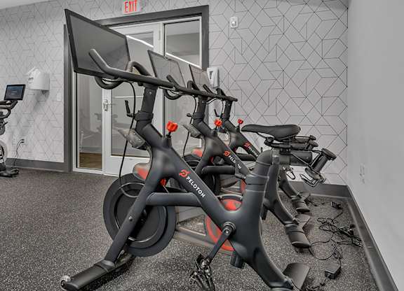 A stationary bike is leaning against a wall in a gym.