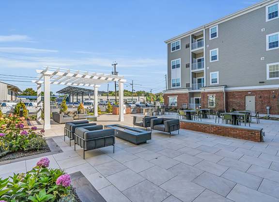 A patio with a white pergola and black furniture.