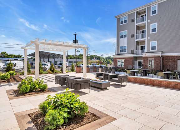 A sunny day at a residential complex with a white pergola and a brick building.