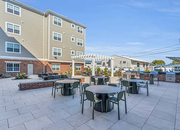 A patio with tables and chairs is surrounded by apartment buildings.