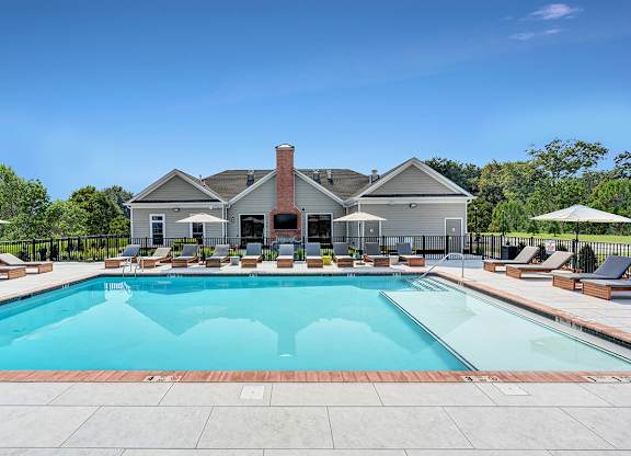A large swimming pool surrounded by lounge chairs and umbrellas.
