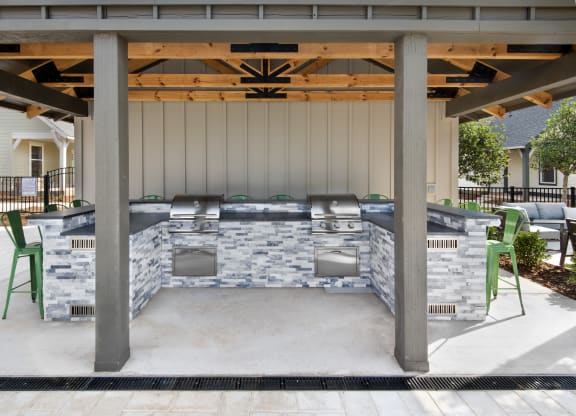 a covered patio with a barbecue grill and chairs