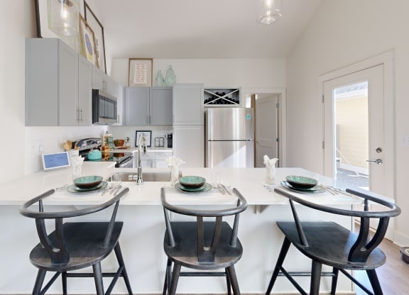 a kitchen with a white counter top and three stools