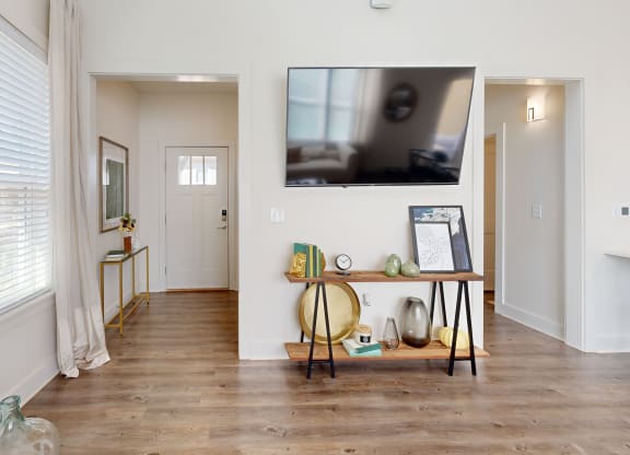 a living room with a tv on the wall and a wooden floor