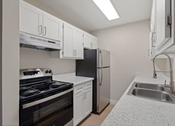 Kitchen with white cabinets and a black stove and refrigerator at Verde Apartments in Tucson, 85719