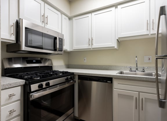 Kitchen with stainless steel appliances and white cabinets at Envue Apartments, Texas, 77802