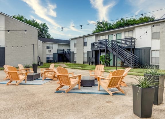 Patio with a fire pit and lounge chairs in front of an apartment building  at The Wick, College Station