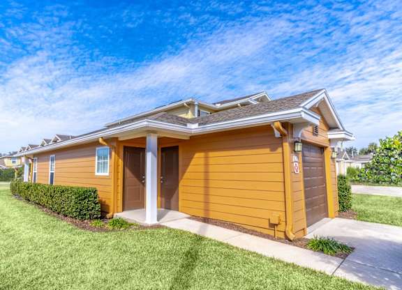 A yellow house with a brown roof and a white door.